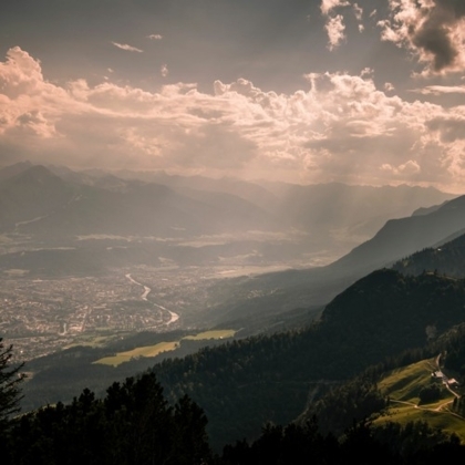 Blick von Berg ins Inntal, mit Wolken und Sonnenstrahlen.